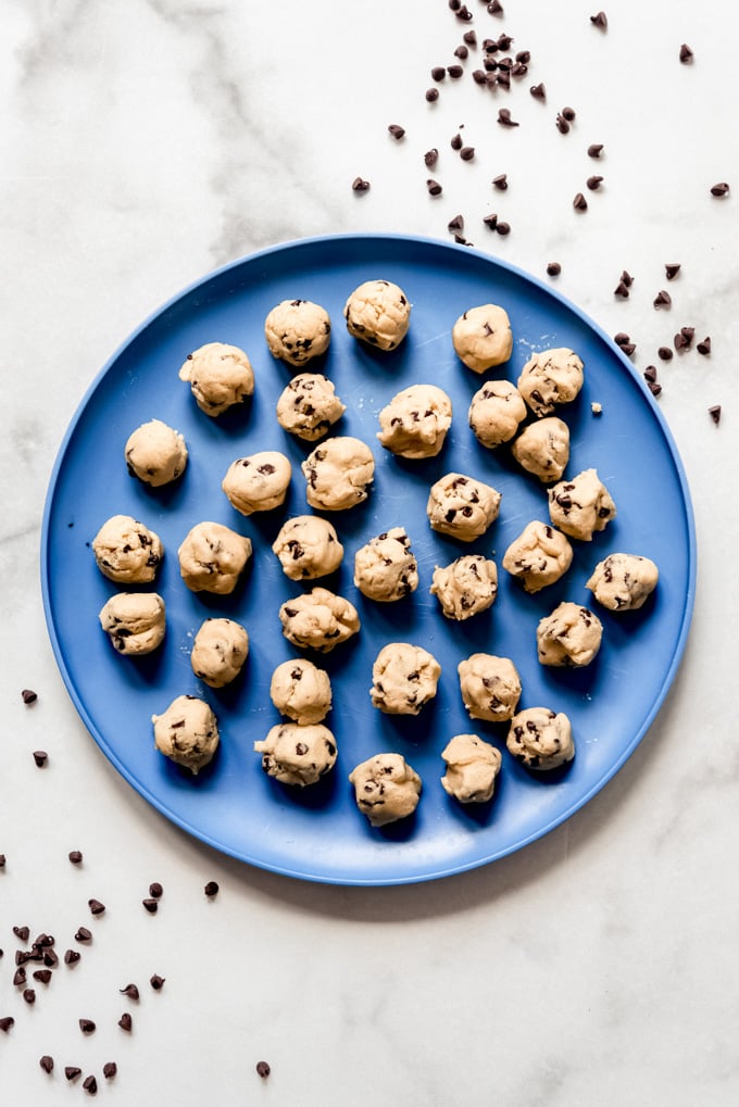 Small balls of chocolate chip cookie dough on a blue plate.