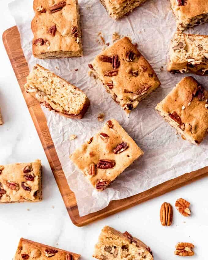 Maple pecan blondies cut into squares and arranged haphazardly on white parchment paper.