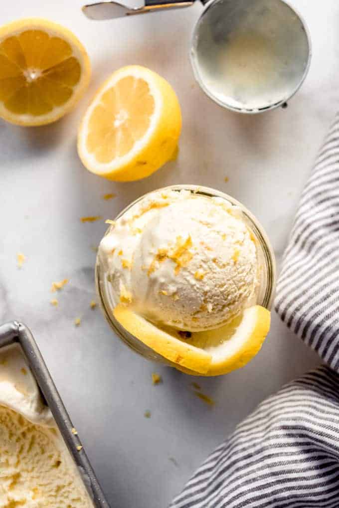 A scoop of lemon ice cream in a bowl with lemon wedges for decoration.