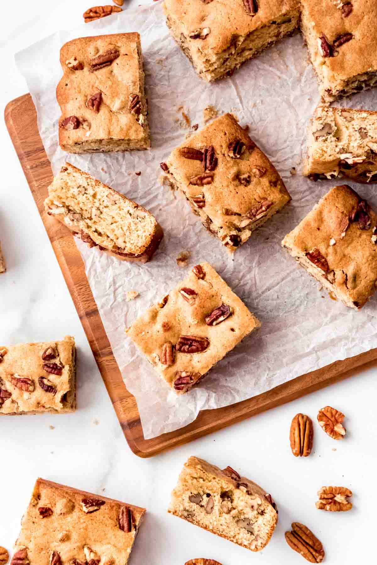 Maple pecan blondies cut into squares and arranged haphazardly on white parchment paper.