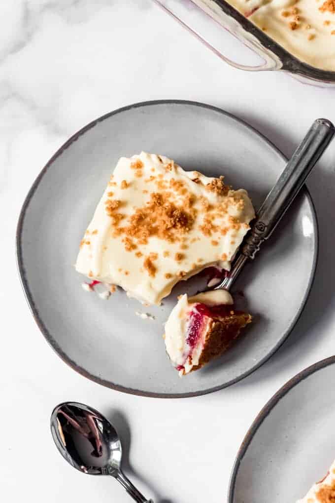 A slice of layered rhubarb pudding dessert on a plate with a bite taken out of it.