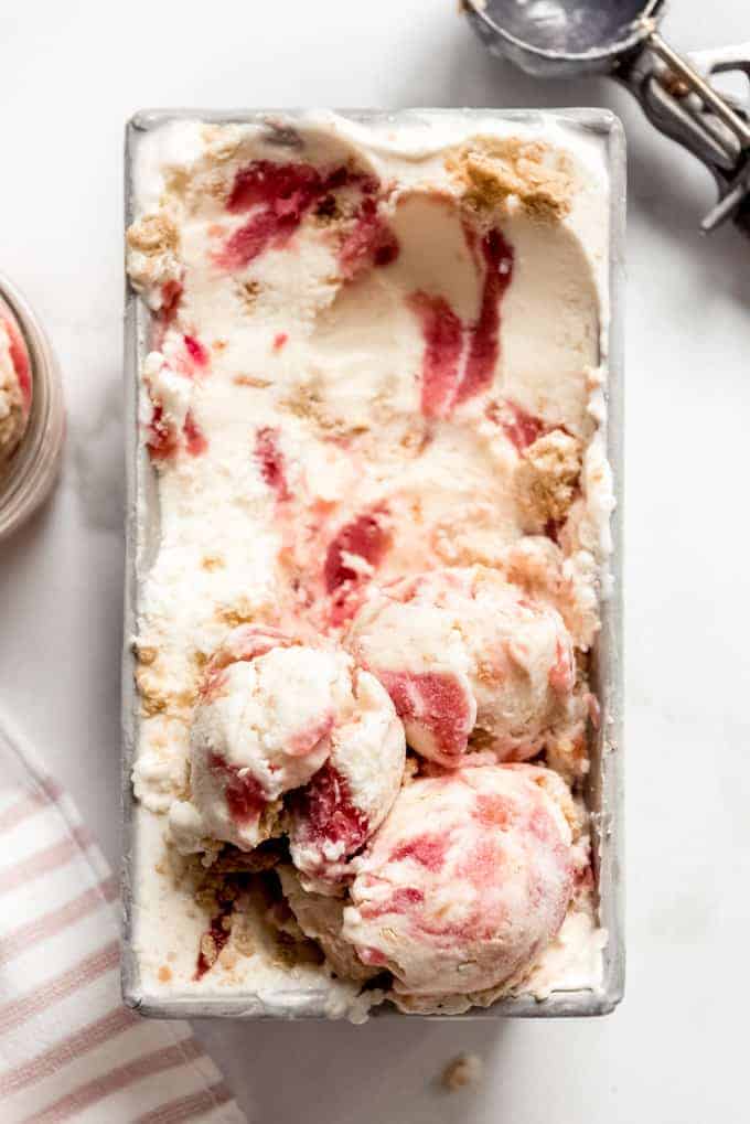 Scoops of vanilla ice cream with a ribbon of rhubarb jam and crumble pieces in it.