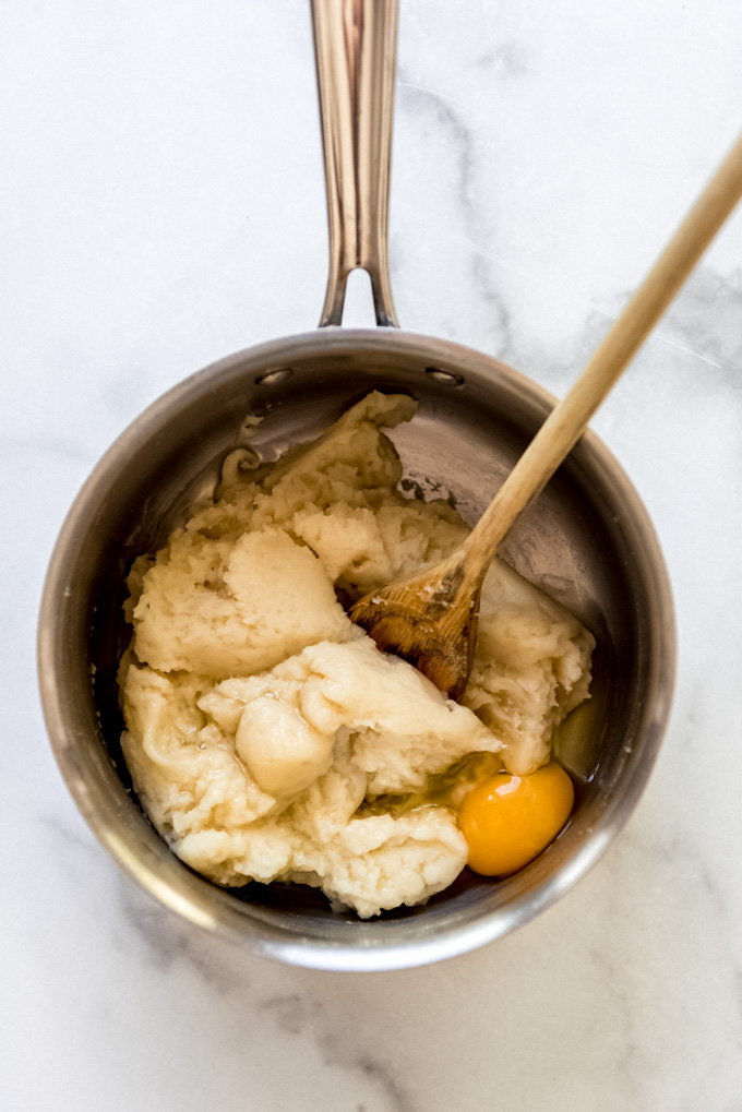 Stirring an egg into the cream puff batter with a wooden spoon