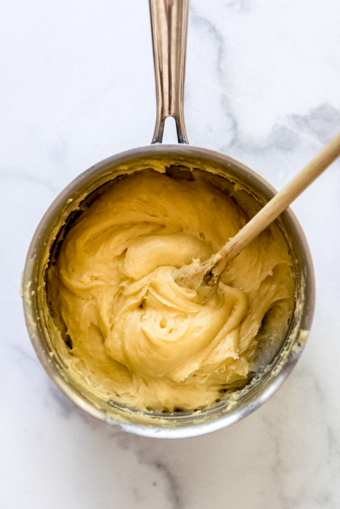 Cream puff batter in a saucepan with a wooden spoon