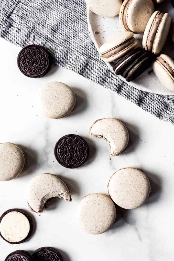 French macarons with bites taken out of some of them next to Oreos.
