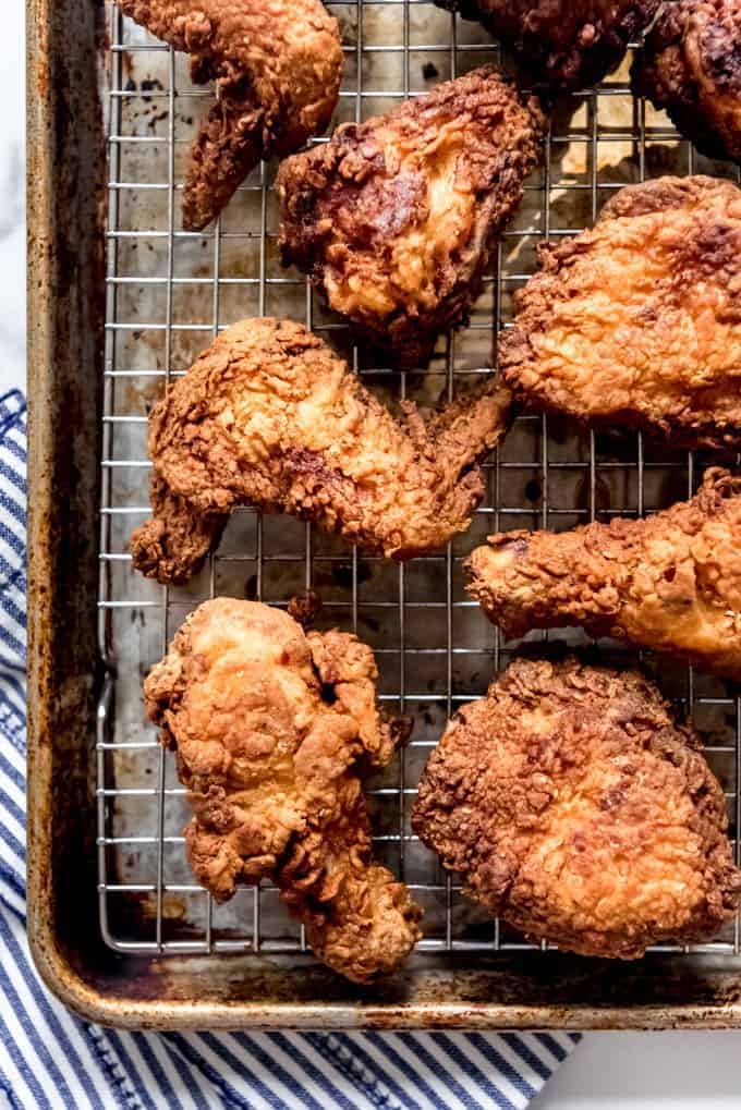 Pieces of fried chicken on a wire rack set over a baking sheet.
