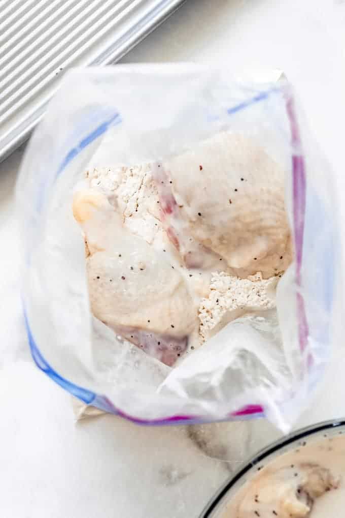 buttermilk covered chicken pieces in a zip tight bag full of flour