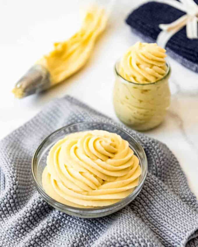 A bowl filled with French pastry cream piped in swirls on a grey cloth.