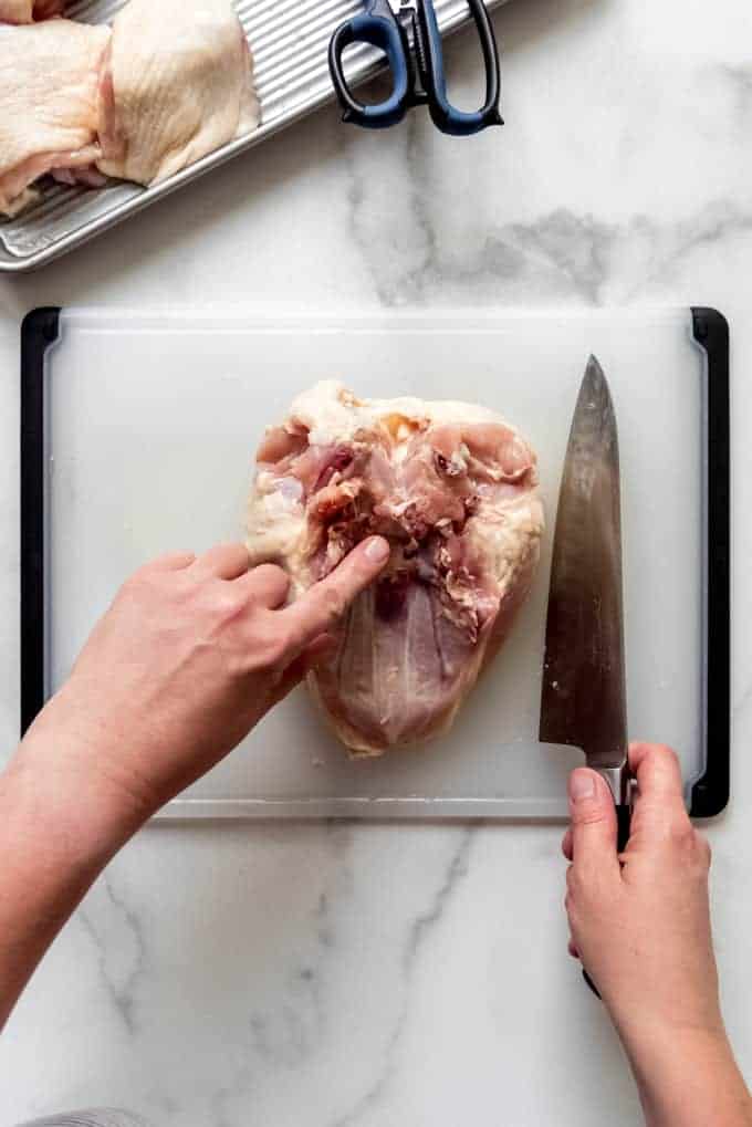 a finger pointing to where to to cut between the chicken breasts to separate them