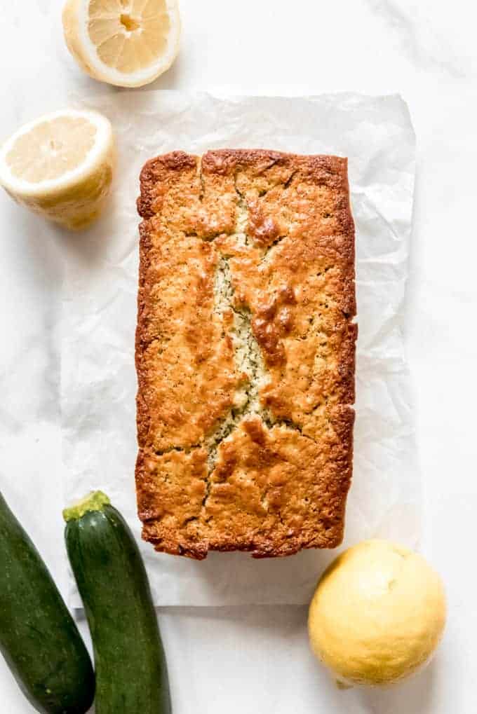an aerial view of baked lemon poppy seed zucchini bread with fresh lemons and zucchinis to the side