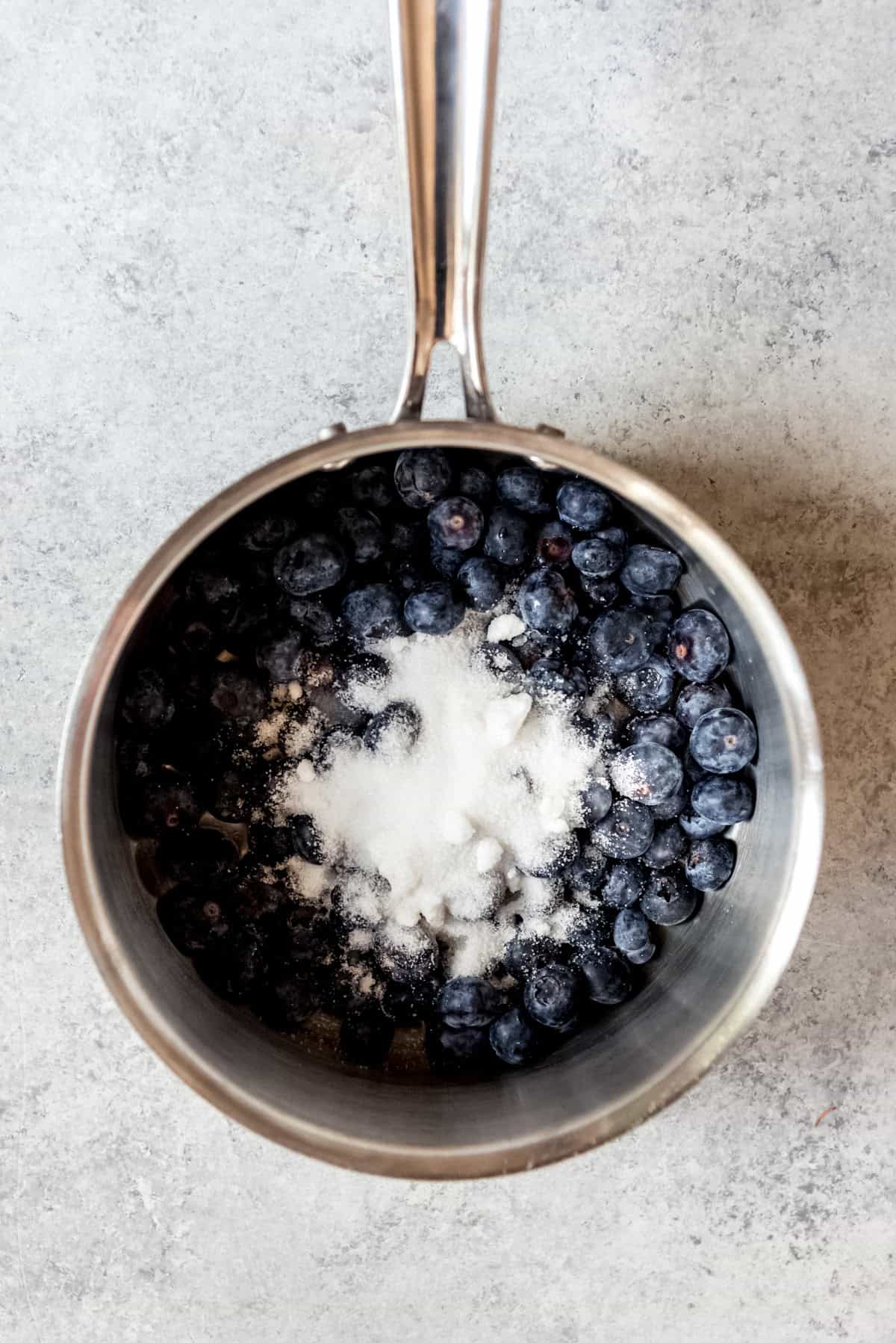 An image of blueberries and sugar in a saucepan.