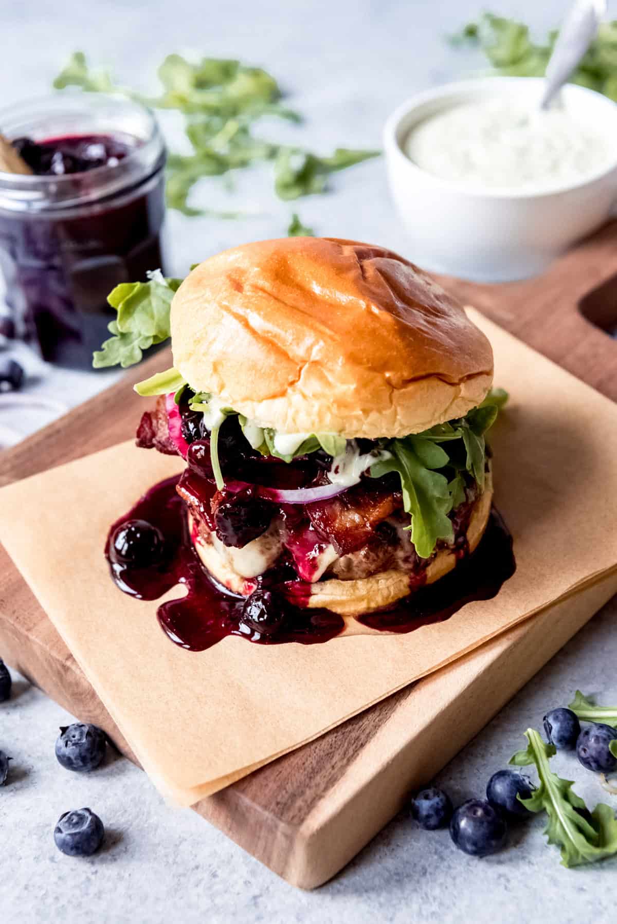 An image of a gourmet burger with blueberry sauce on a cutting board.