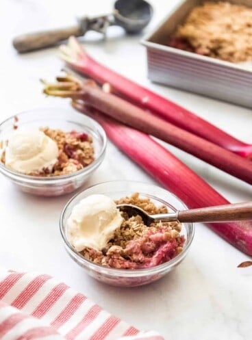 Bowls of rhubarb crisp with scoops of vanilla ice cream.