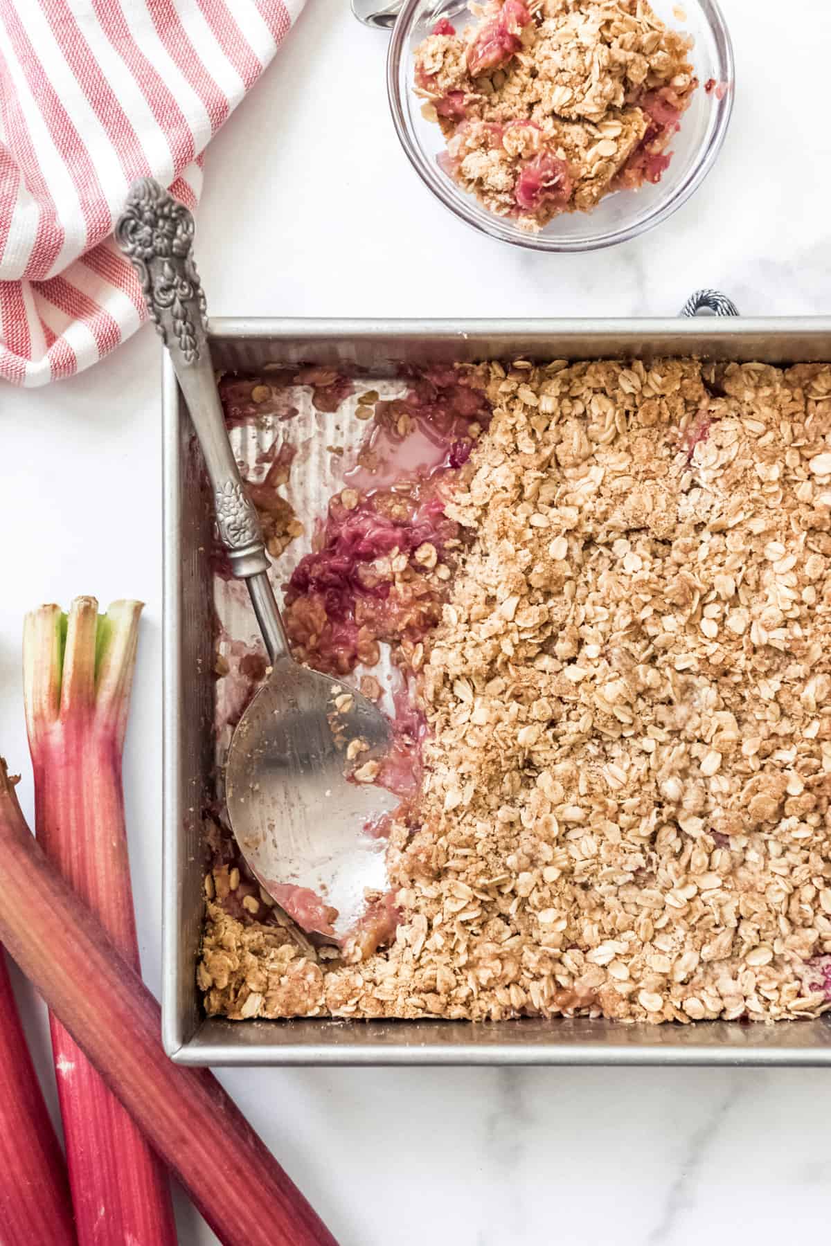 A baking dish with rhubarb crisp and a large serving spoon.