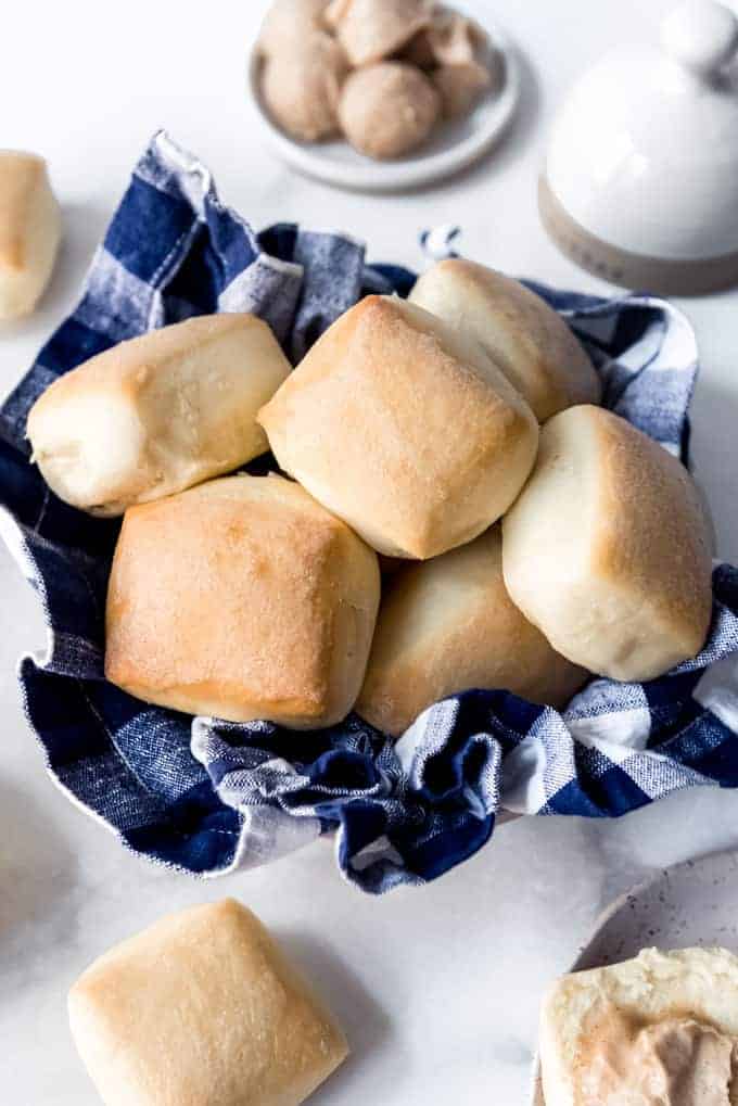 Soft square rolls in a bowl with a cloth napkin.