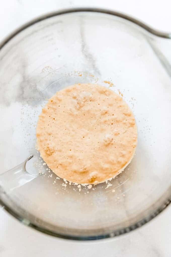 Foamy looking proofed yeast in a large glass bowl
