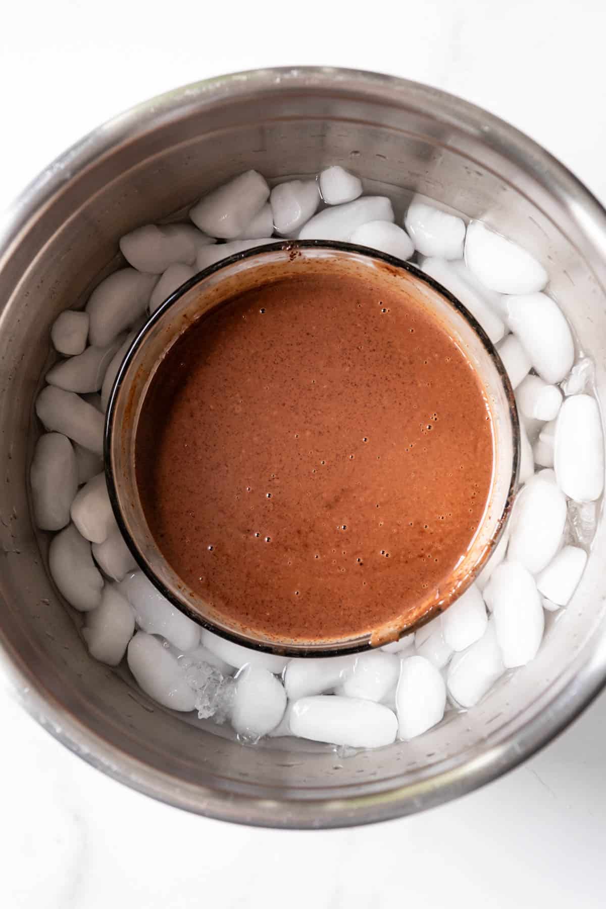 A bowl of chocolate ice cream base in an ice bath.