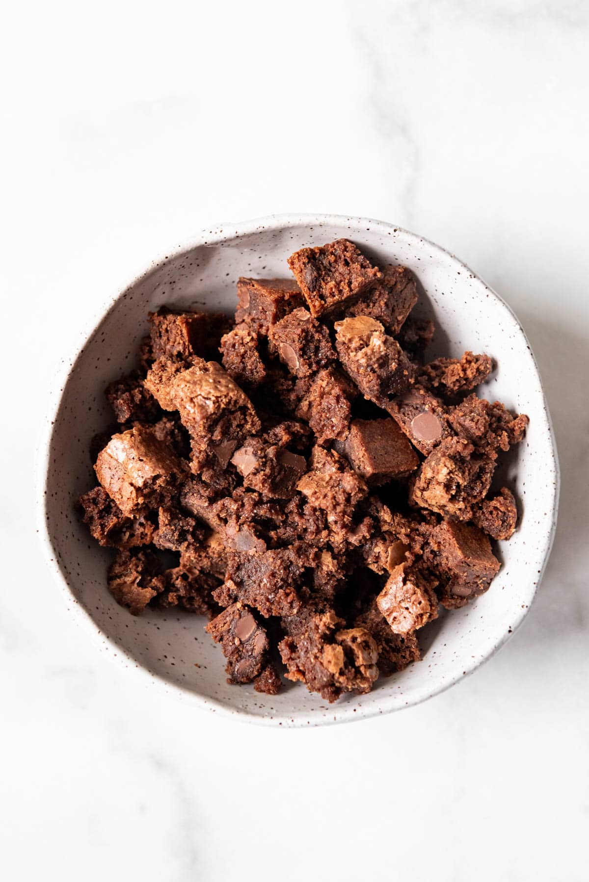 A bowl full of chocolate brownie pieces.