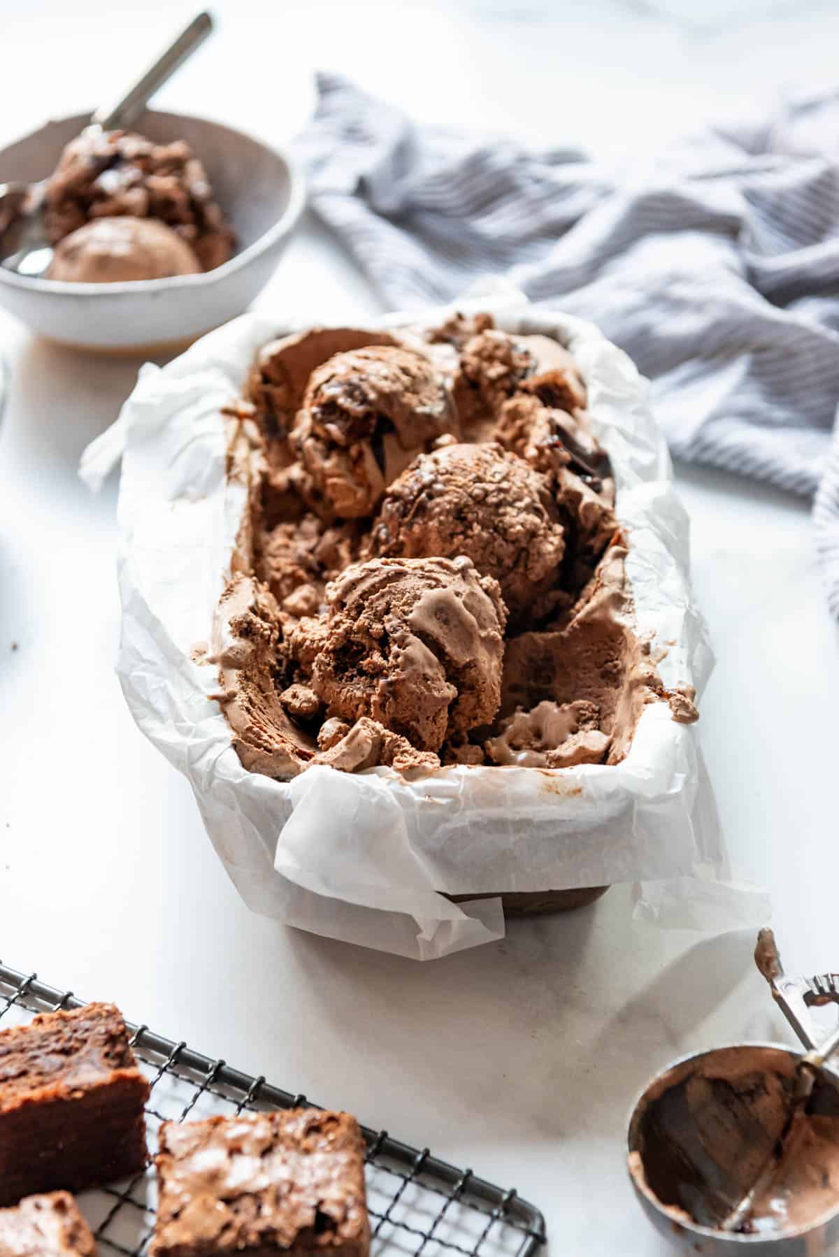 A pan full of homemade chocolate brownie ice cream with big scoops on top.