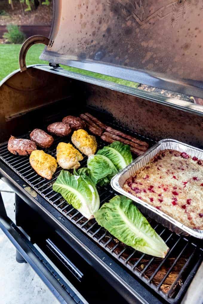 A full meal of sweet potatoes, chicken, lettuce, and dump cake being cooked on a Traeger smoker.