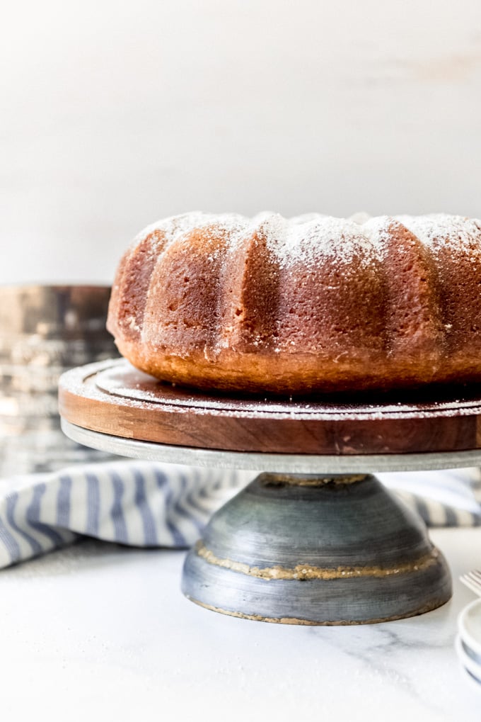 A bundt cake dusted with powdered sugar on a cake stand.