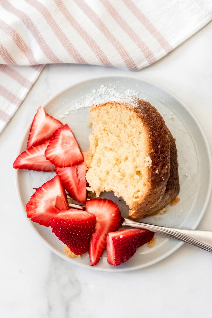 A slice of Kentucky butter cake on a plate with sliced strawberries.