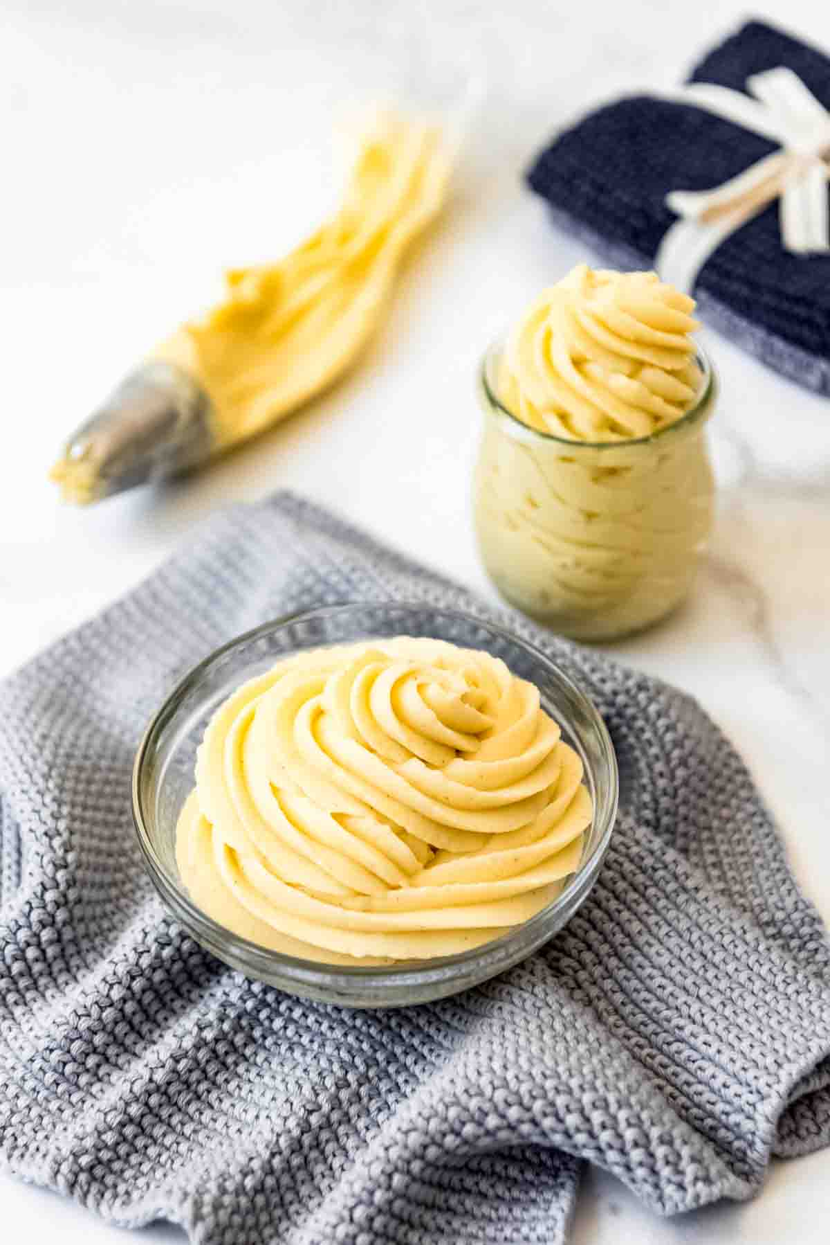 A bowl filled with French pastry cream piped in swirls on a grey cloth.