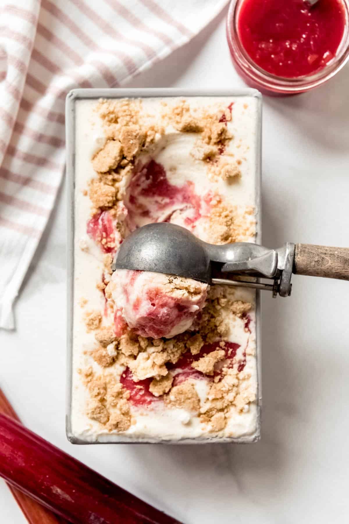 An ice cream scoop being used to scoop homemade rhubarb crumble ice cream.