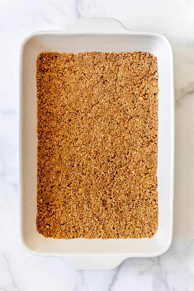 pressed graham cracker and pecan crust in the bottom of a large white baking pan