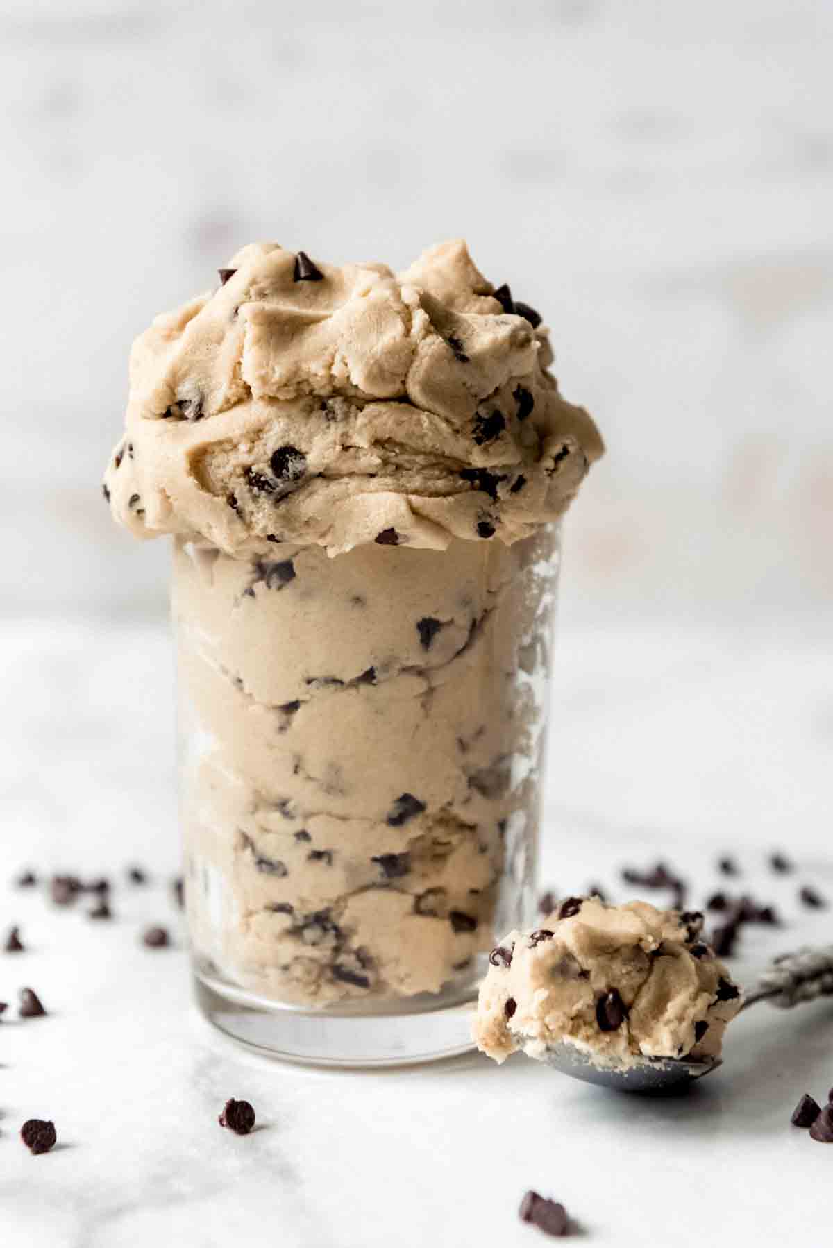 A mound of edible chocolate chip cookie dough next to a spoonful of dough.