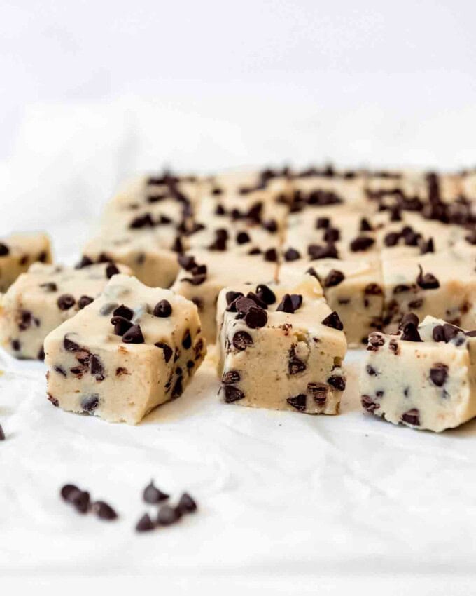 Squares of cookie dough fudge on white parchment paper.