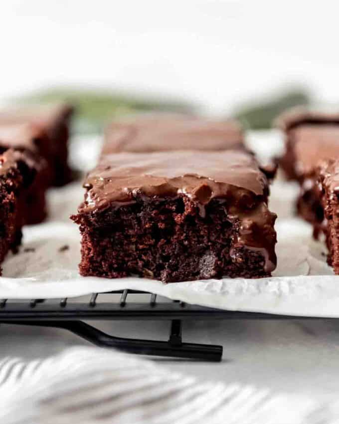 A close image of a moist zucchini brownie with chocolate icing.