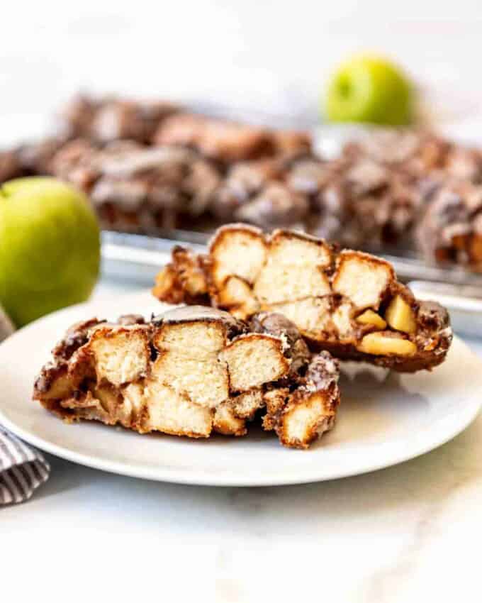 An apple fritter cut in half on a white plate.