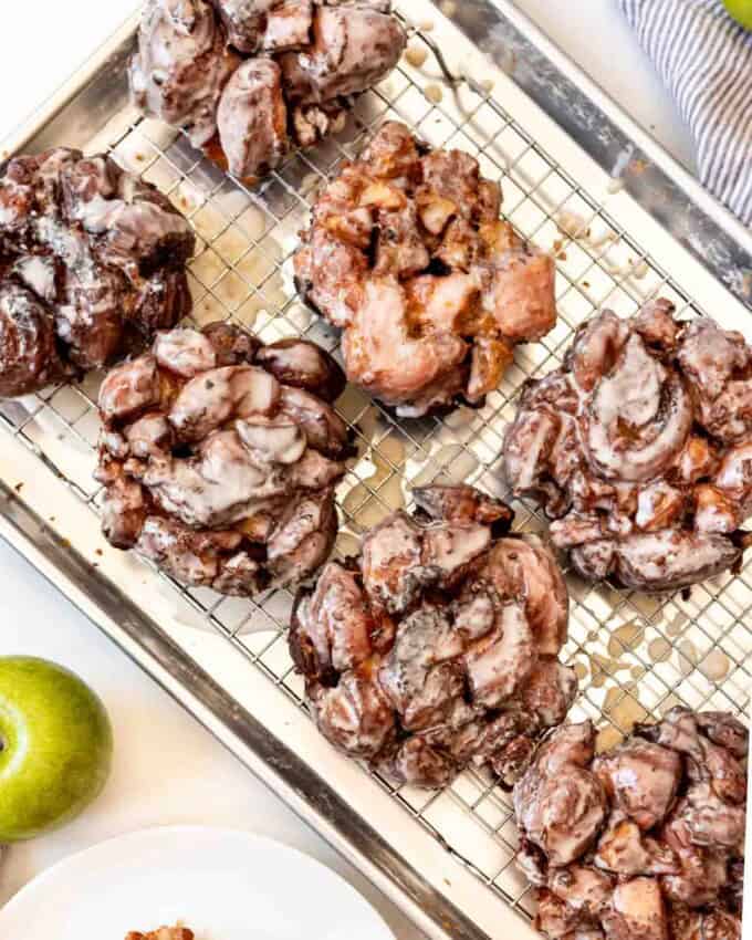 Glazed apple fritters on a wire rack.