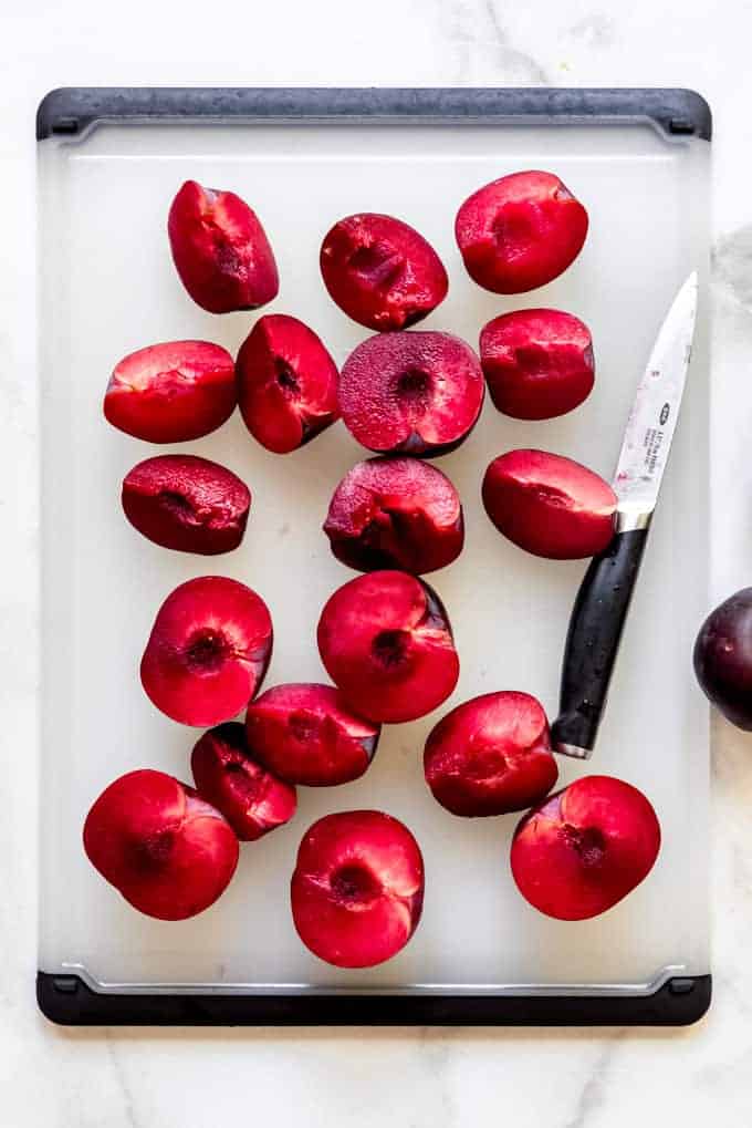 Sliced plums on a cutting board with a small knife.