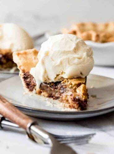 A slice of Kentucky Derby Day Pie with a scoop of vanilla ice cream melting on top.