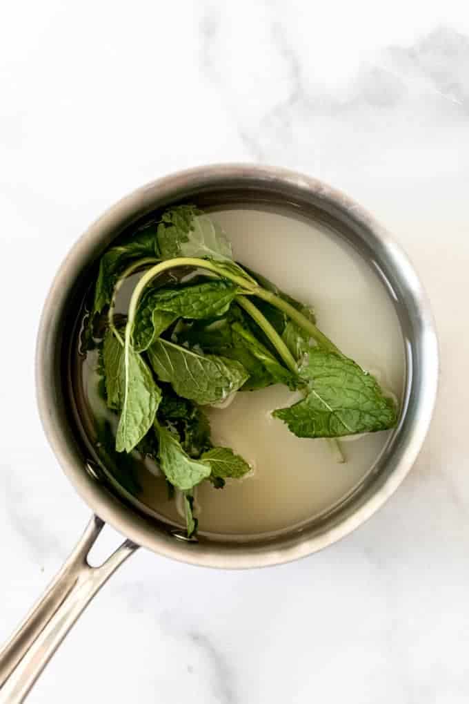 Mint leaves in a small pot with sugar and water.