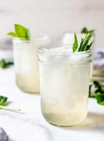 Glass mason jars filled with crushed ice for mint juleps garnished with mint leaves.