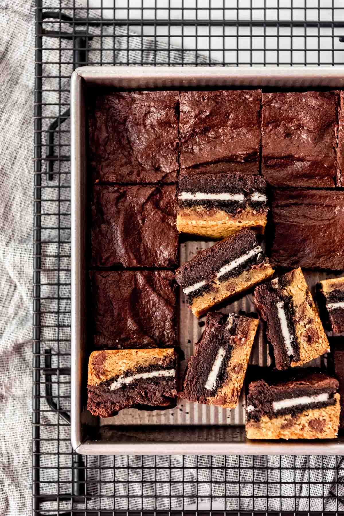 Brownies with cookie dough on the bottom and Oreos in the middle in a pan.