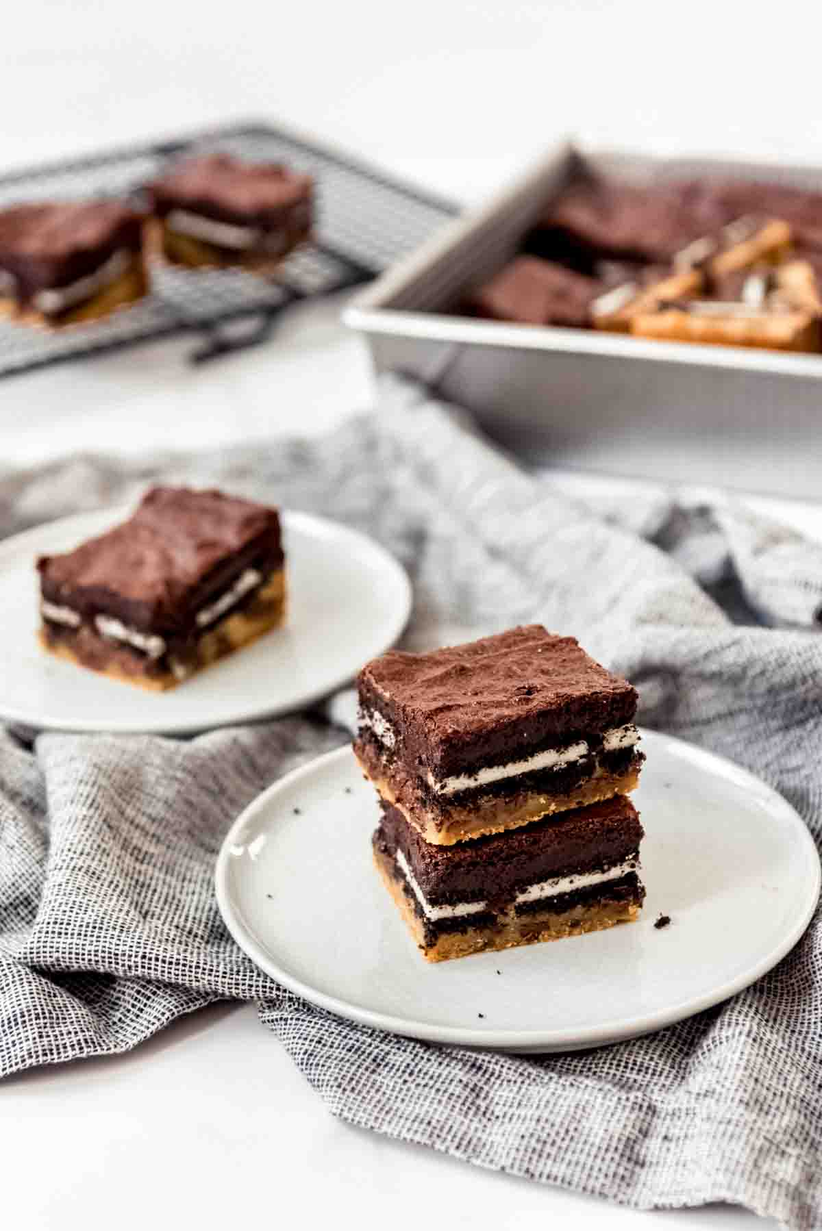 3-layer brownies with chocolate chip cookies on the bottom, Oreos in the middle, and brownies on top, on white plates.