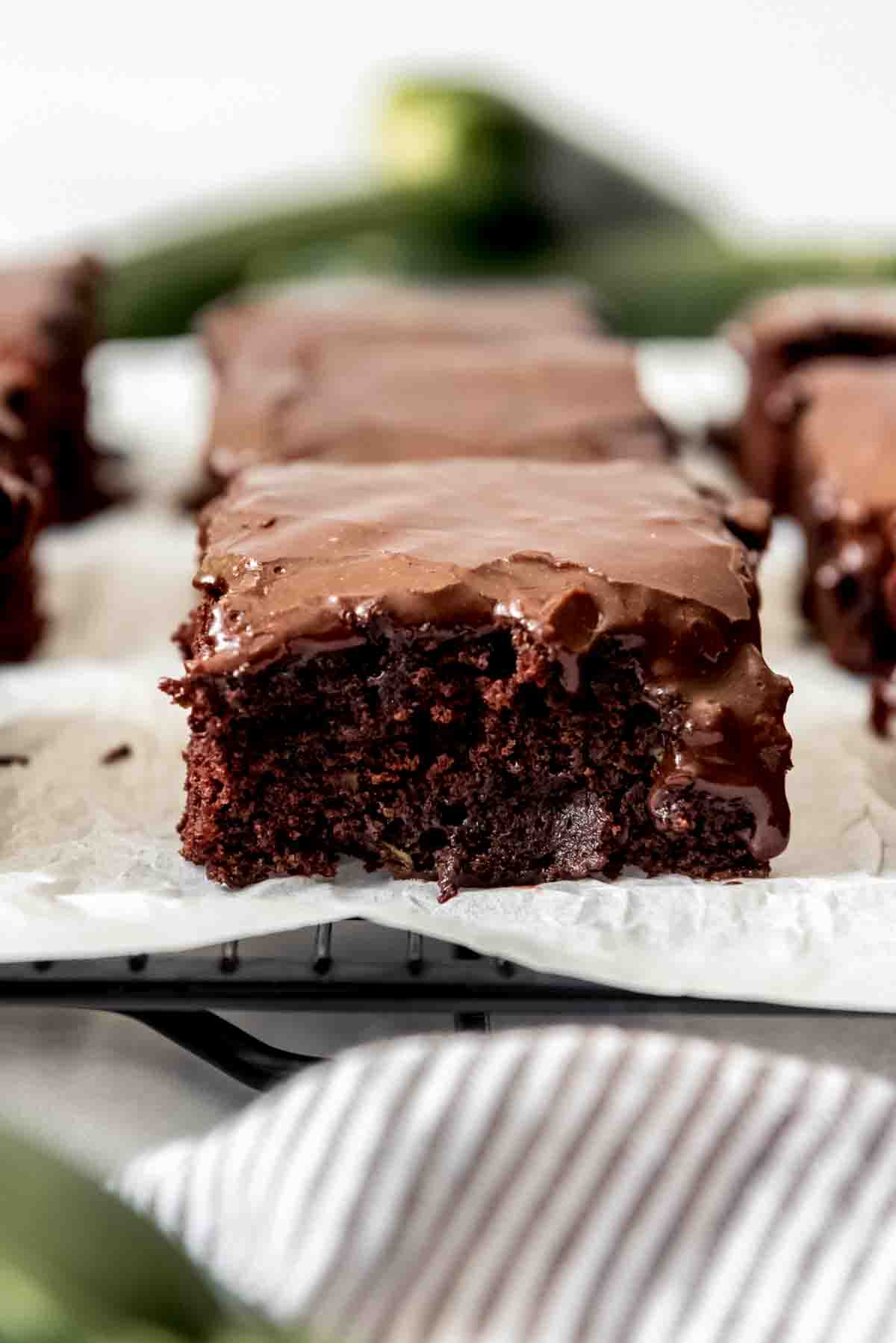 A close image of a moist zucchini brownie with chocolate icing.