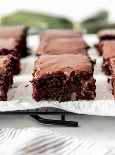 A close image of a moist zucchini brownie with chocolate icing.