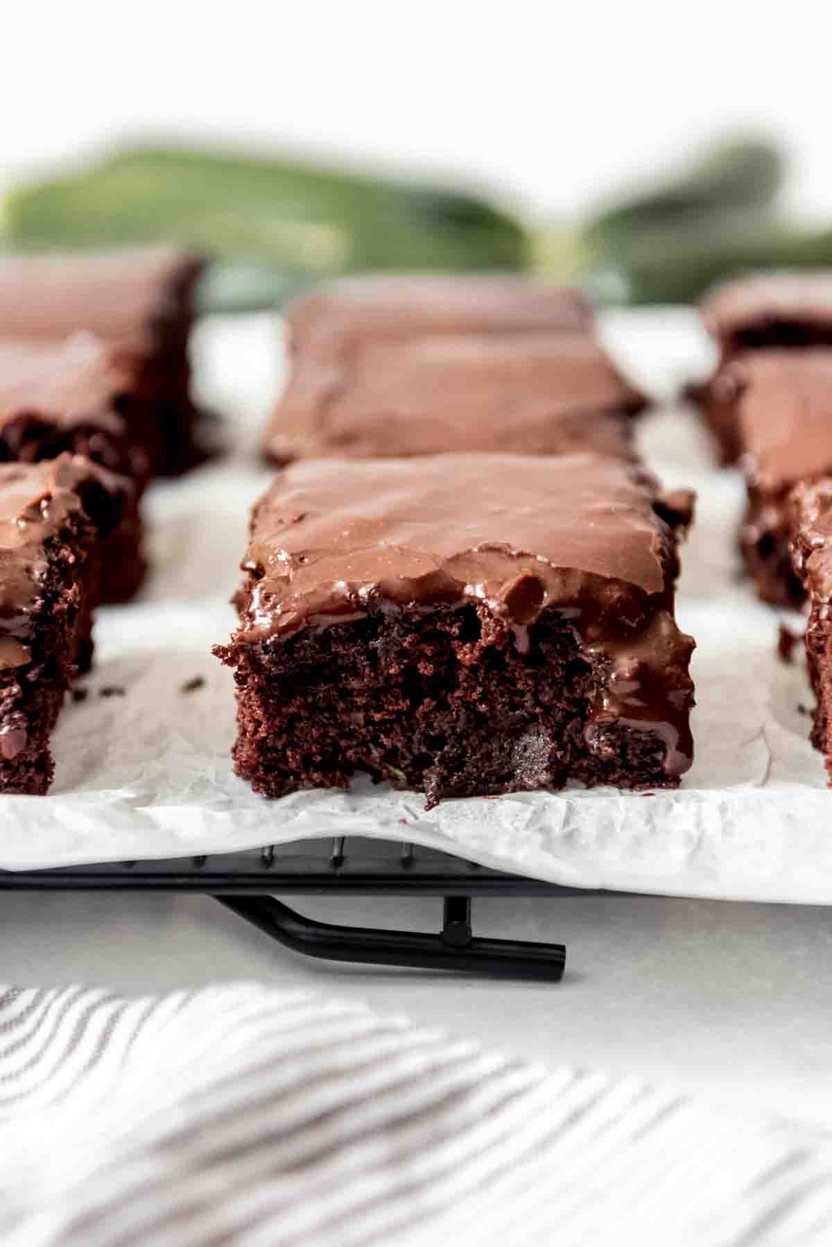 A close image of a moist zucchini brownie with chocolate icing.