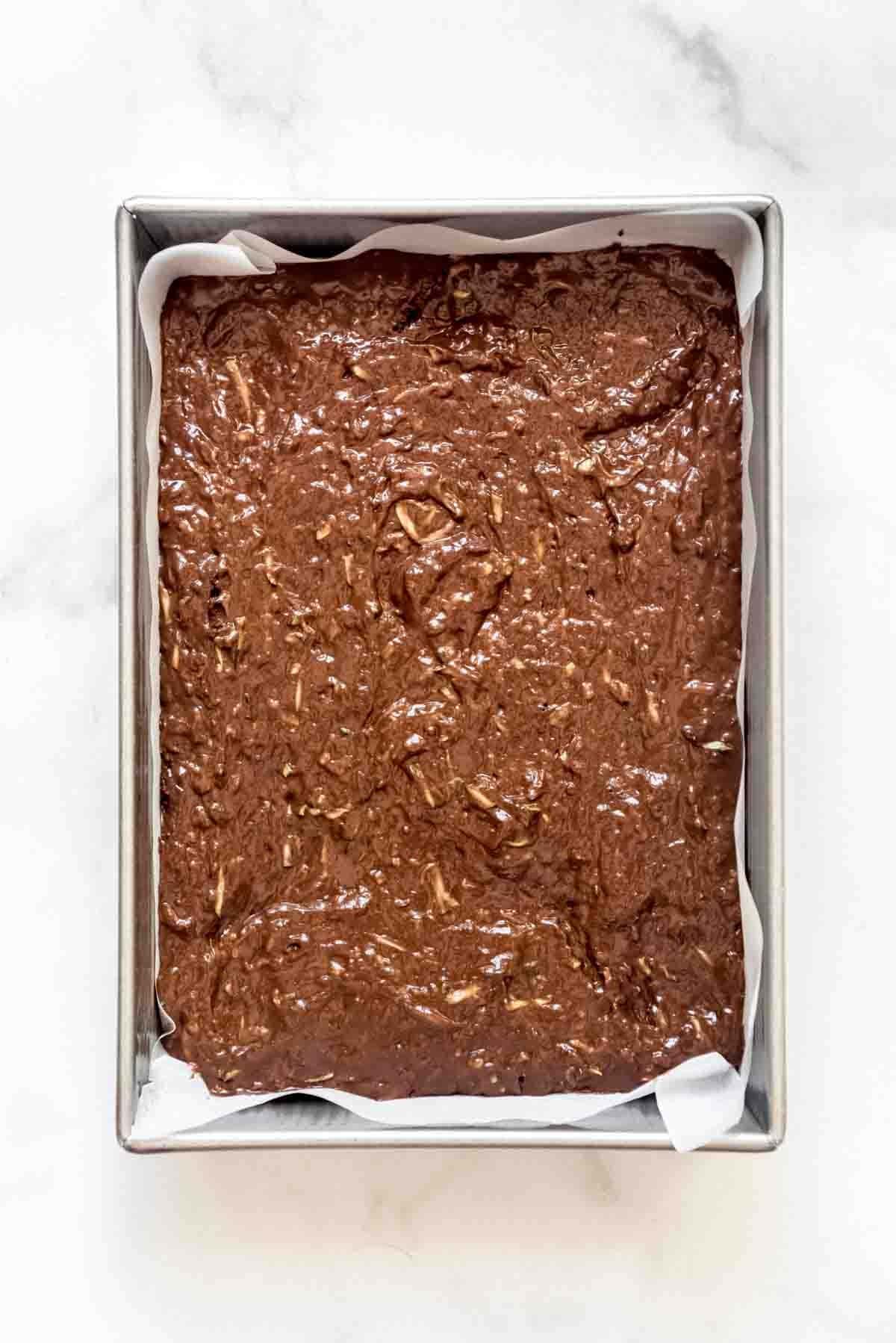 A baking dish filled with zucchini brownie batter.