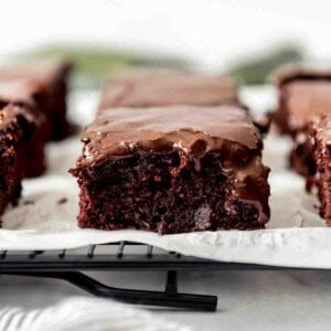 A close image of a moist zucchini brownie with chocolate icing.