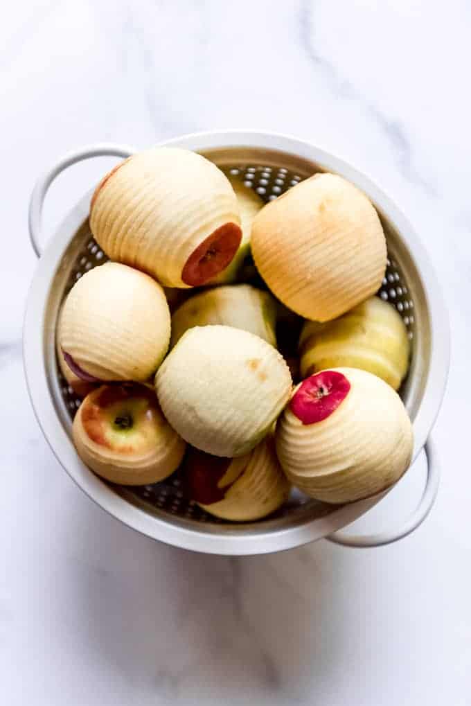 Peeled apples in a white colander.