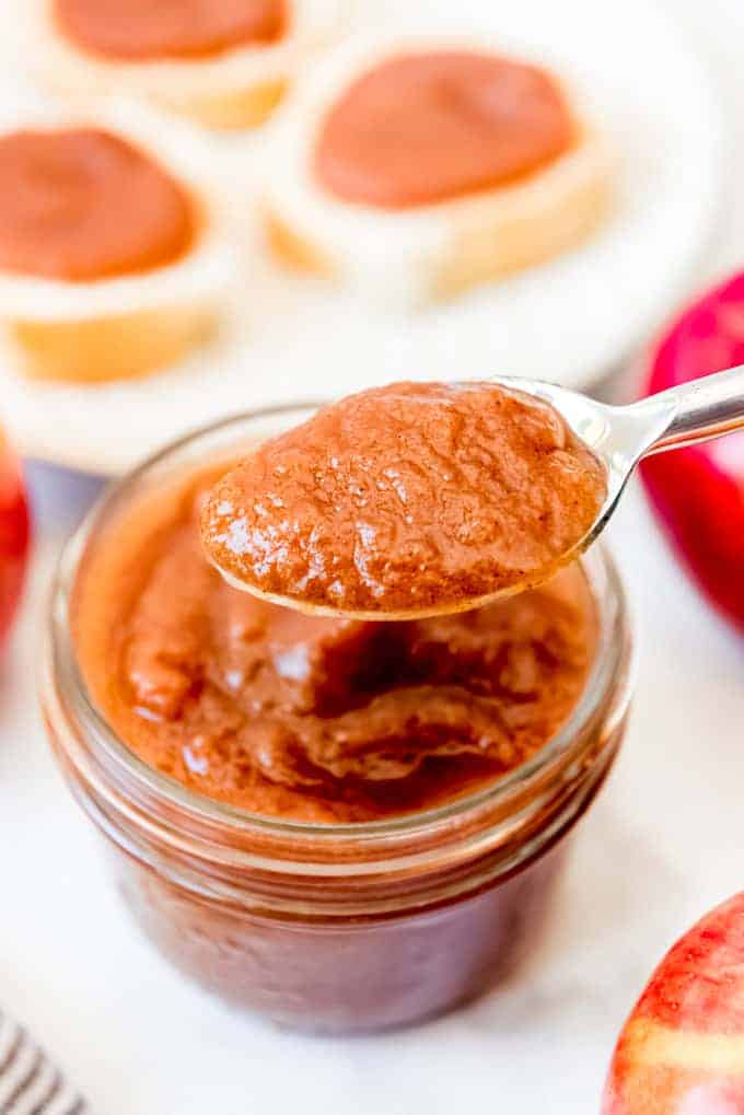 A spoonful of apple butter over a jar of apple butter.