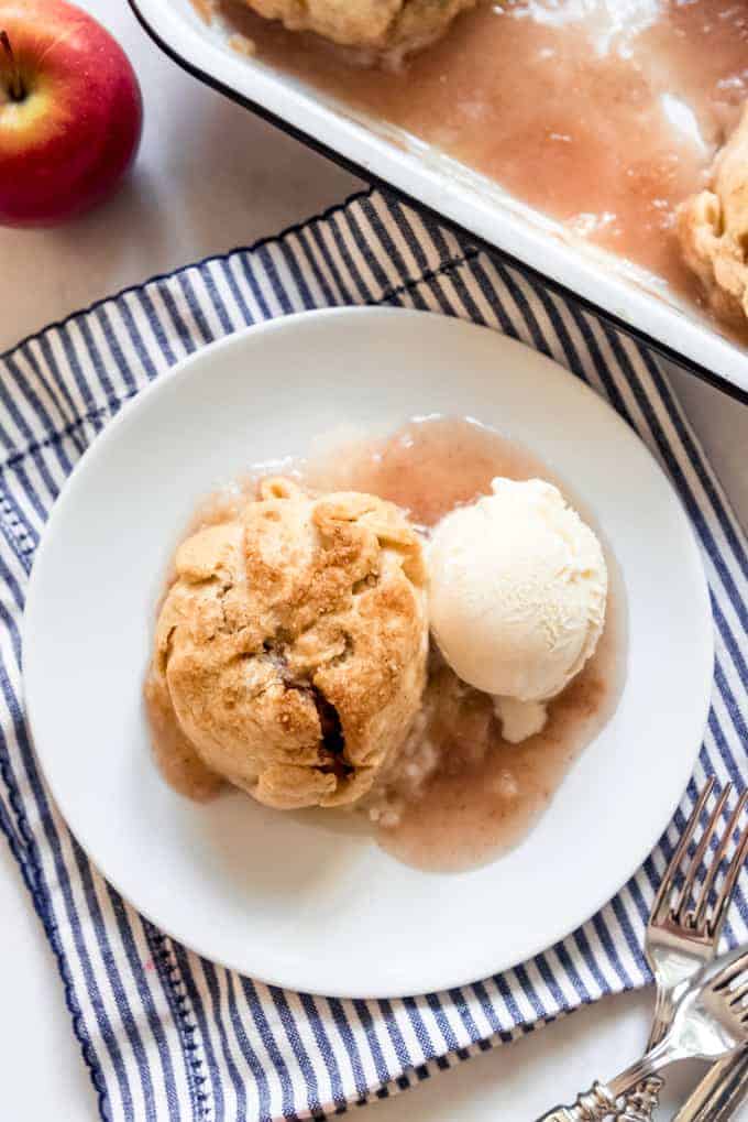 An apple dumpling on a white plate with a scoop of vanilla ice cream.