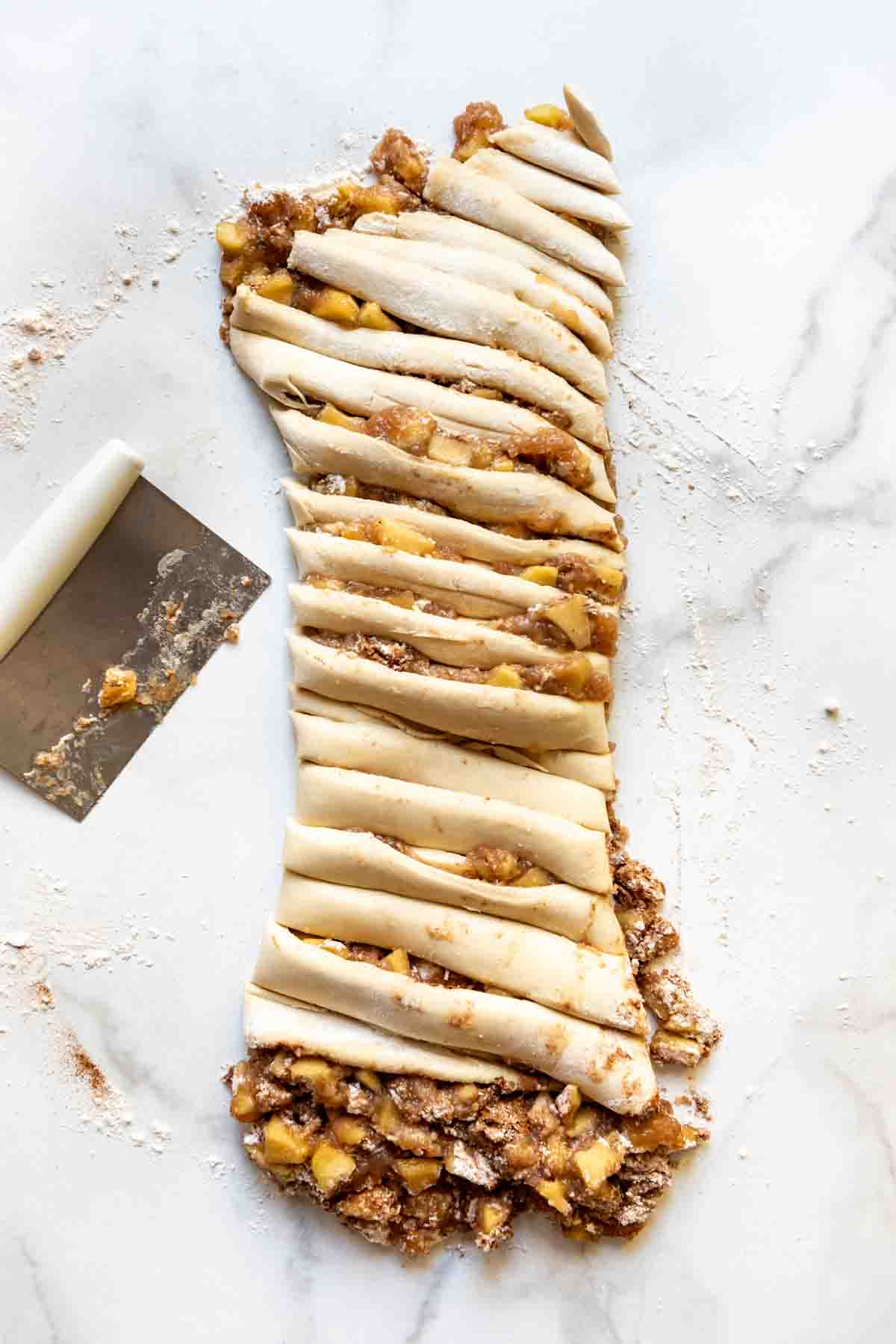 a rolled log of dough filled with apple filling inside and sliced into several pieces with a pastry cutter to the side