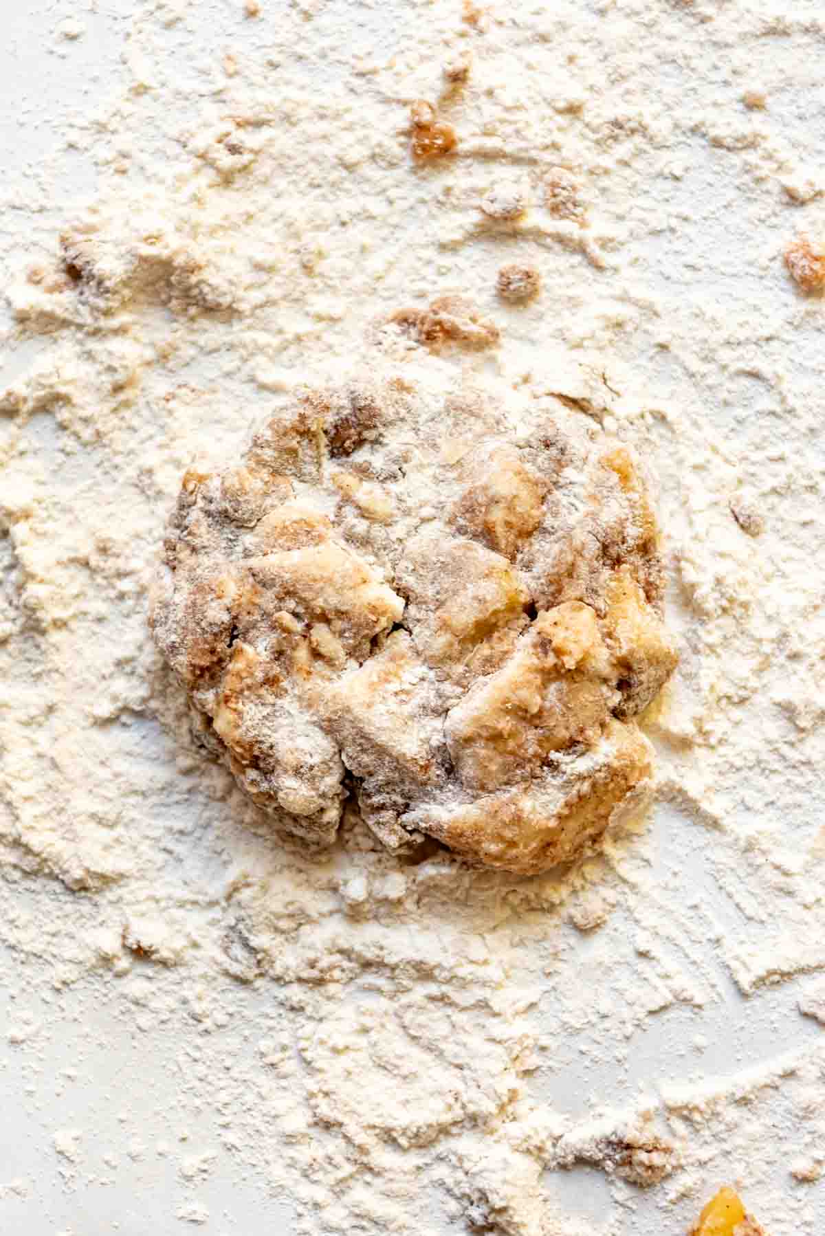 Apple fritter dough on a floured surface.